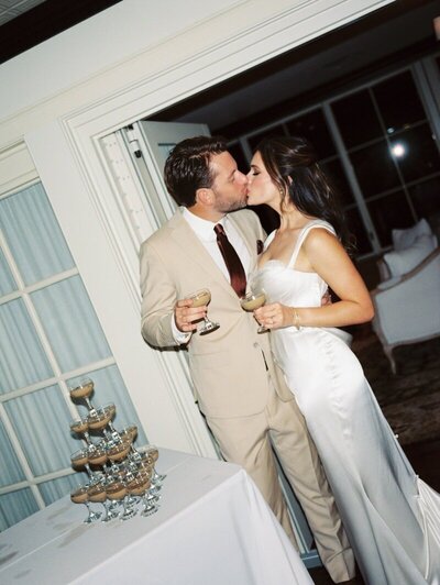 image by tom thornton photography in minneapolis minnesota bride and groom kiss on their wedding day while holding drinks