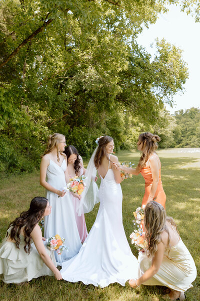 Bride surrounded by bridesmaids adjusting her dress