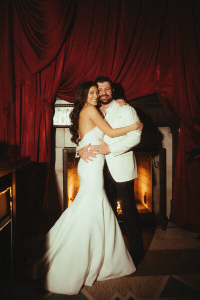 Bride and groom at nighttime wedding reception in front of bold red drapery styled by Arizona wedding planner