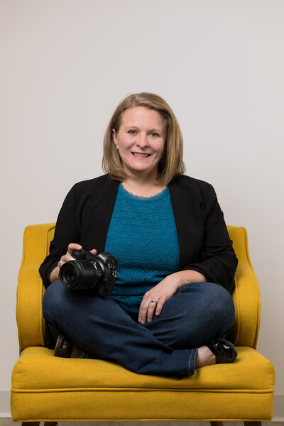 woman sitting in a chair with a camera