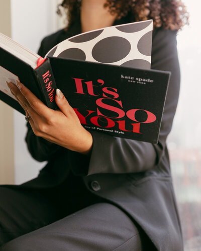 Catryce flipping through a colorful and bold pattern book in a pantsuit