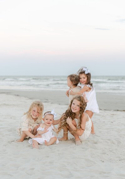 A group of children candidly playing during an extended family photography session on a beach during sunset on Hilton Head, South Carolina, captured by Hilton Head Photographer Lamp and Light Photography by Danielle Puckhaber.