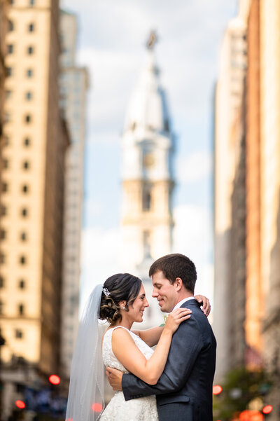 Bride and groom standing in the middle of broad street in Philadelphia with city hall behind them