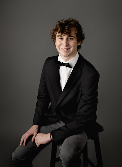 Formal Senior graduation photo of boy smiling at camera. Photo taken at Atlanta photo studio by Jenni Nikki Photography.