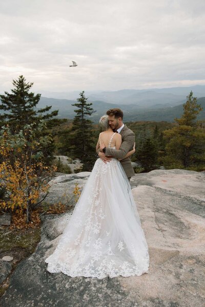 Bride and Groom Hug on a Cliff In White Mountains