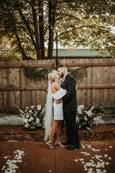 bride and groom kissing by array of flowers