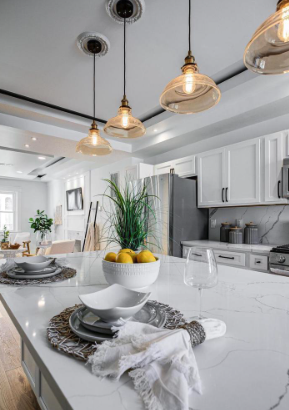 Modern kitchen remodel featuring a quartz waterfall island, custom white cabinetry, stainless steel appliances, and designer pendant lighting—crafted for both elegance and everyday living.