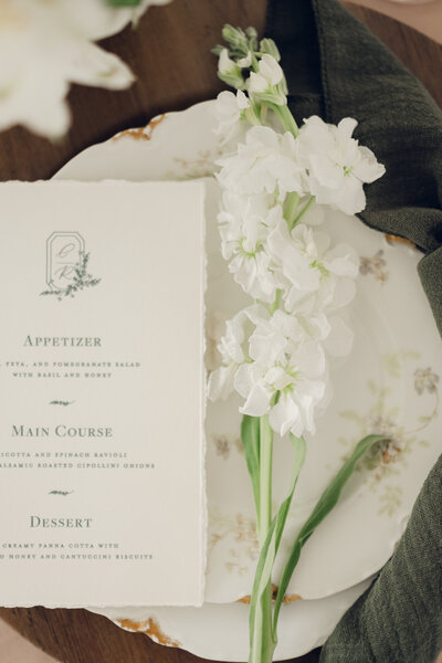 Elegant wedding menu with delicate white flowers on vintage plate