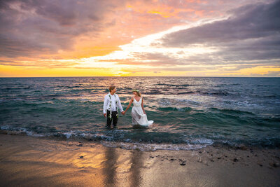 Couple holding hands in ocean at Kukio Beach, taken by big island Hawaii photographers at Hawaii Adventure Portraits