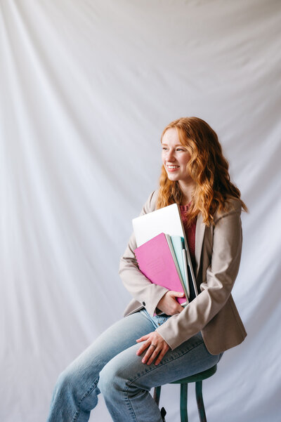 Emma, a brand and website designer, holding papers and a laptop