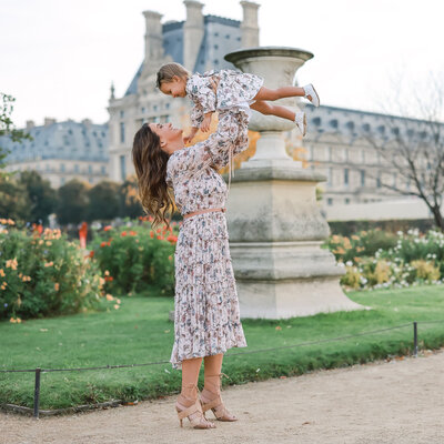 Mother lifts her daughter in the air wearing matching dresses photographed by Dale Benfield Photography in Paris France