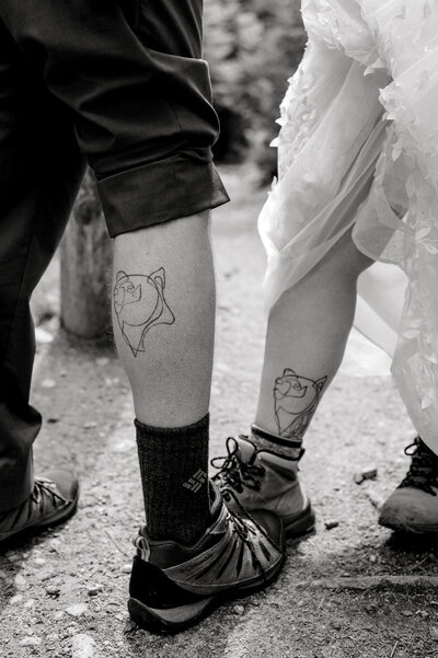 Black and white image of couple's matching leg tattoos at Acadia elopement