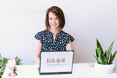 brand photo of a business owner posing in her office, laptop opened