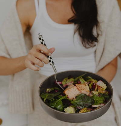 Picture of women holding a bowl of nutritious food like salmon, beets, spinach and more