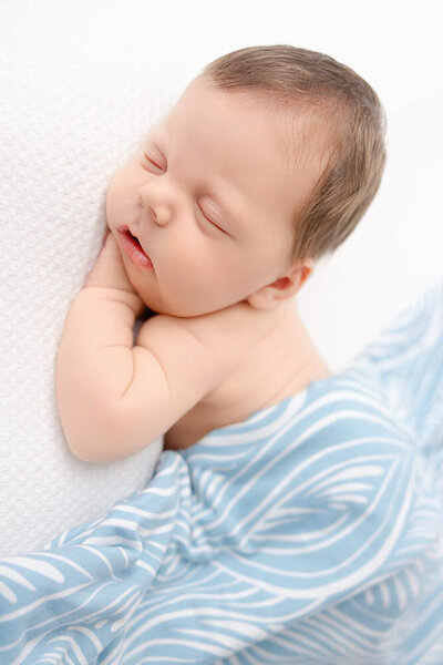 Pregnant mom wearing a white long dress with hands placed above and bellow belly.