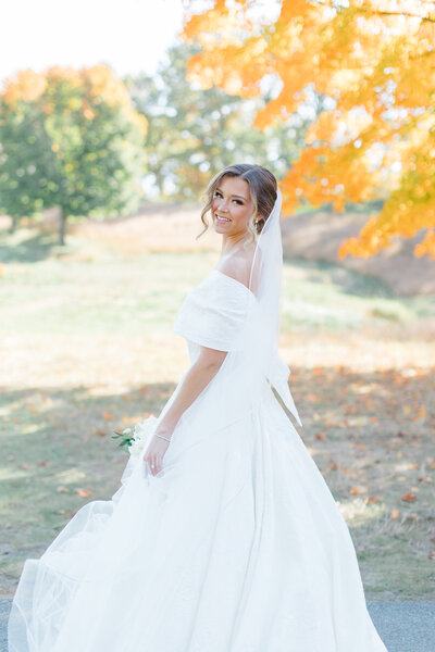 Bride posing for a portrait underneath a yellow tree