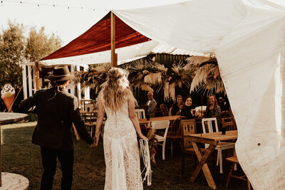 bohemiskt brudpar går in i glampingtält på deras utomhusbröllop i tyskland