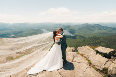 A bride and groom kissing on the summit of Whiteface Mountain near Lake Placid New York