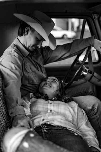 Black and white picture of Laura looking up at Jacob as he smiles down at her while sitting in the cab of his vintage truck.