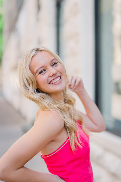 Blonde high school senior wears a pink top while playing with her hair in downtown Chattanooga.