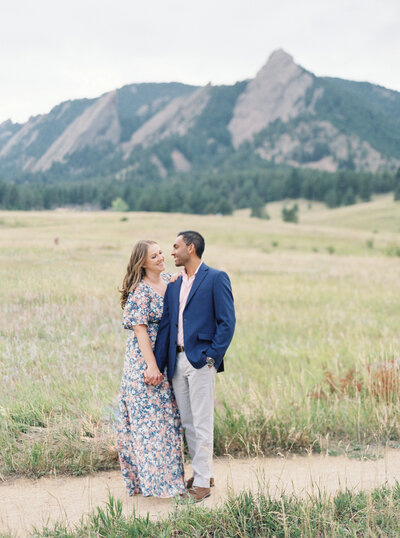 Couple smiling in front of mountains in field Denver Family Photographer