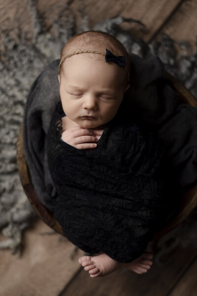Newborn baby girl wrapped in a black velvet blanket