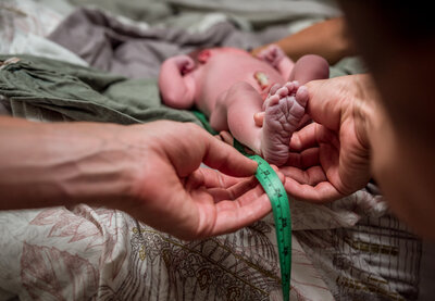 Measuring newborn baby’s foot during in-home postpartum care following a natural birth