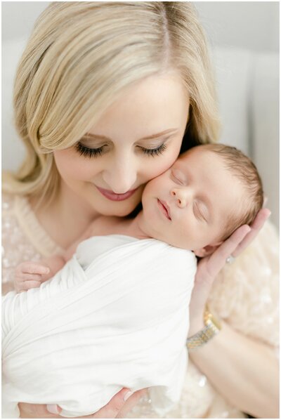 mom holding baby baby close to cheek during newborn session
