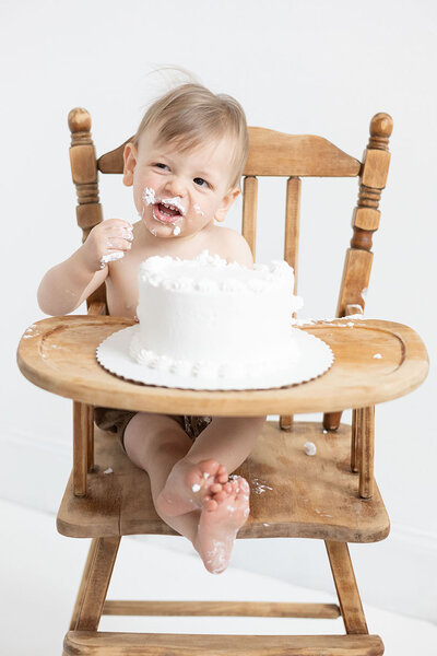 Little boy sitting in a highchair during cake smash for milestone session during NH Baby Photography session with Kathleen Jablonski Photography