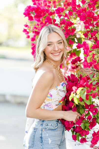 young woman smiling by a flower bush