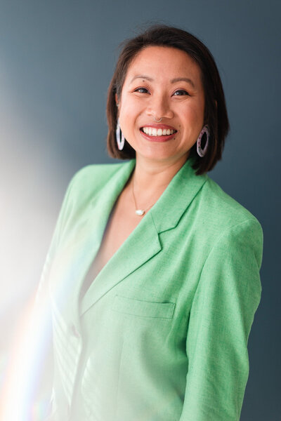 woman in a green suit jacket smiling