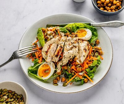Grilled chicken salad with leafy greens, chickpeas, carrot, seeds, and boiled egg – a fertility-boosting meal to support egg quality at 35+.