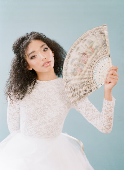 Black woman with vintage fan on blue background