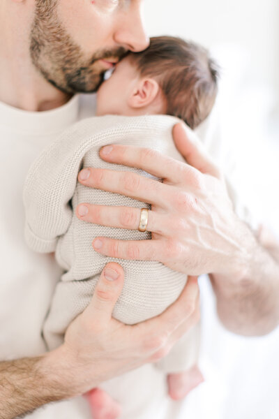 A mother lays on her bed and gazes down at her baby while being photographed by New Jersey Newborn Photographer Kate Voda