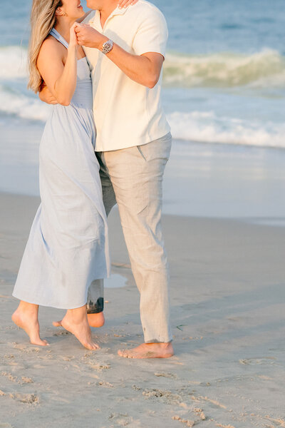 couple holding hands on beach during engagement photos