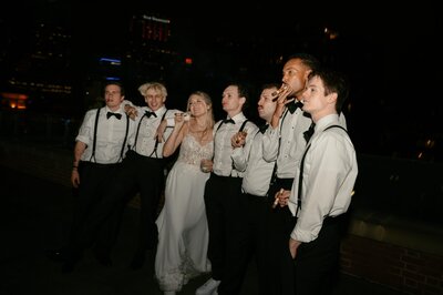 bride posing with all of the groomsmen