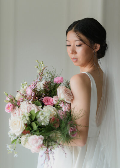 asian bride for a chic city wedding at the fairmont hotel. Bride looks down at pink and white florals with soft lips.