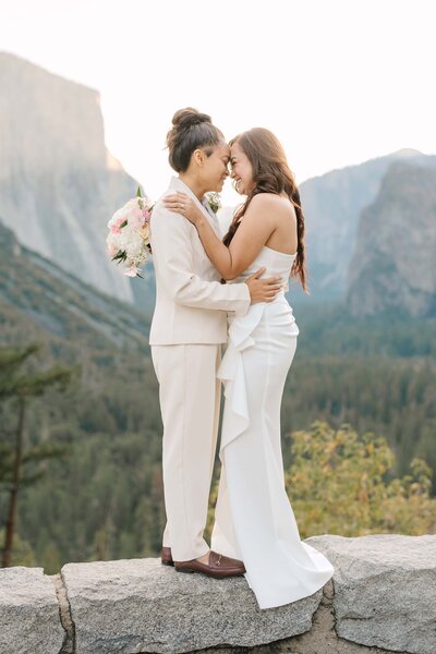 Lesbian wedding couples snuggles at sunrise during their elopement at tunnelview in Yosemite.