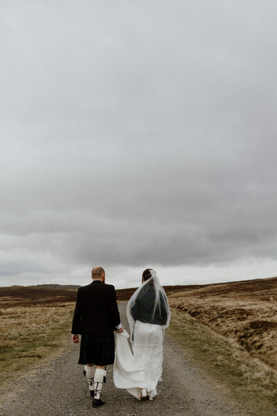 bride and groom walk down track road