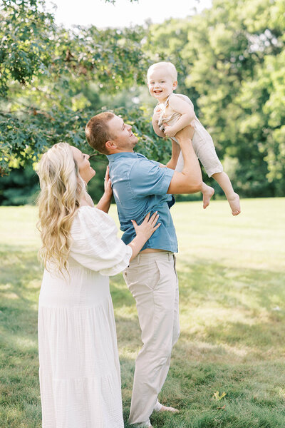 Husband lifts up baby boy with wife for summer photos in Lancaster.