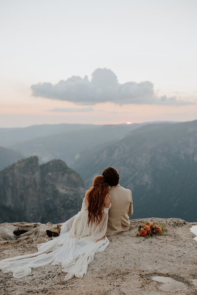 bride and groom watching the sunset on a rocky overlook resting heads together