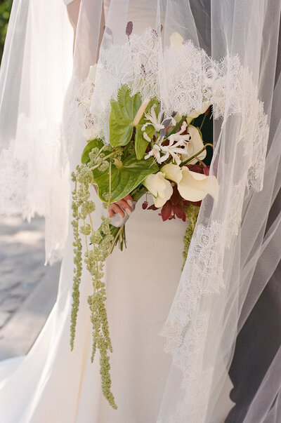 The bride and groom pose gracefully in front of a vintage car on a grassy field at their Brighthouse Farm wedding. She dazzles in a lace gown with flowers, while he looks sharp in a dark suit. As the trees and cloudy sky provide a picturesque backdrop, this moment is beautifully captured by Toronto's destination wedding photographer, Jennifer van Son.