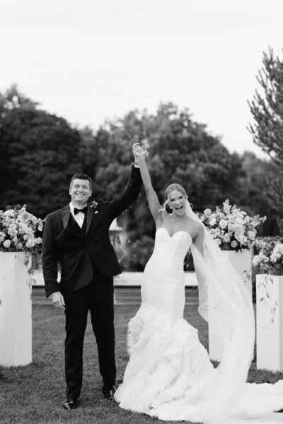 Black and white image of newly wed couple smiling down the aisle