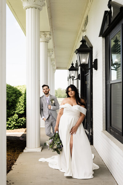 Bride and groom holding hands around a wall, anxiously waiting for their first look, capturing the moment before they see each other for the first time on their wedding day.