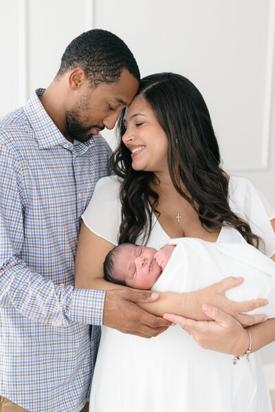 New mom wearing a cream Nothing Fits But dress holding her newborn baby boy  in a timeless northern kentucky newborn photography studio