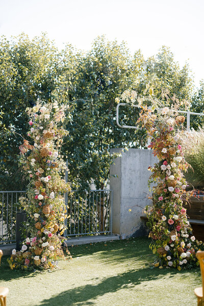Broken Arch fall wedding floral installation in copper, pink, mauve, cream, and green colors. Roses and fall branches highlight these fall wedding florals. Design by Rosemary and Finch in Raleigh, NC.