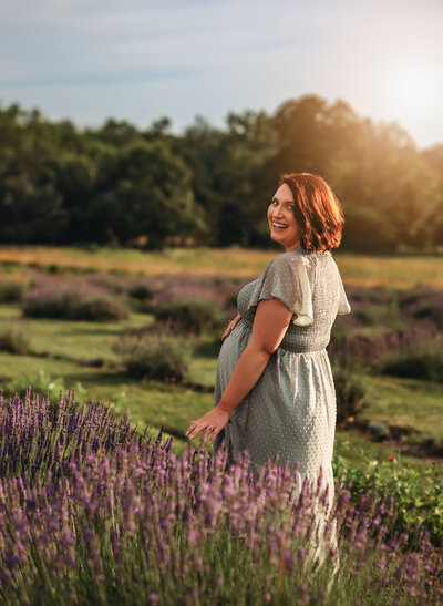 A man and woman stand together with eyes closed and touching foreheads. The woman is pregnant and they're both holding her belly. They're in a snowy field with mountains in the background for maternity pictures.