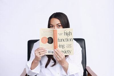A woman sits in a chair, reading a book, reflecting a moment of calm amidst her therapy research for OCD and anxiety in New Jersey.