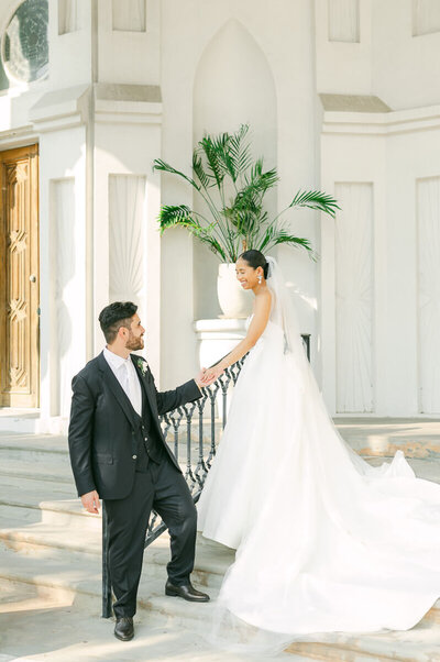 Groom helping bride down steps at Sacred Heart Catholic Church