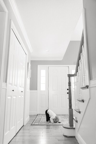 black and white photo of a little girl trying to do a summersault during her in-home portrait session